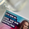 Ausschnitt eines Plakats zum BESTFORM AWARD mit dem Slogan „Ich bin in Bestform. Zeig, wie wir Zukunft gestalten!“ – daneben ein Glas und ein Teil eines Gesichts.