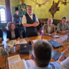Landrat Götz Ulrich steht in einem historischen Raum der Rudelsburg und spricht zu einer Gruppe von Personen am Tisch, darunter Sachsen-Anhalts Innenministerin Dr. Tamara Zieschang, Thüringens Innenminister Georg Maier und weitere Landräte. Im Raum: Jagdtrophäen an der Wand, grüne Kachelöfen und Tageslicht durch ein Rundbogenfenster.