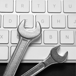 Zwei Schraubenschlüssel liegen auf einer Computertastatur und symbolisieren die Behebung einer technischen Störung und die Wiederherstellung von IT-Systemen.