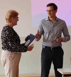 Ehrenamtskoordinator Christian Rößler übergibt eine Lesepaten-Mappe an Lesepatin Anke Bach aus Droyßig.