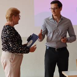 Ehrenamtskoordinator Christian Rößler übergibt eine Lesepaten-Mappe an Lesepatin Anke Bach aus Droyßig.