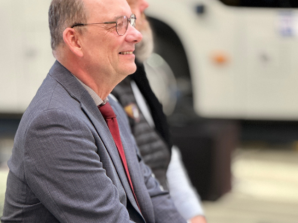 Lutz Däumler, langjähriger Geschäftsführer der PVG, bei seiner Verabschiedung in den Ruhestand, im Vordergrund lächelnd im grauen Anzug mit roter Krawatte.