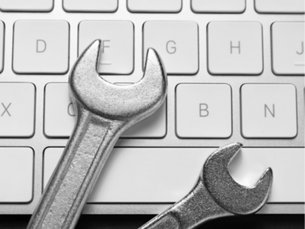 Zwei Schraubenschlüssel liegen auf einer Computertastatur und symbolisieren die Behebung einer technischen Störung und die Wiederherstellung von IT-Systemen.