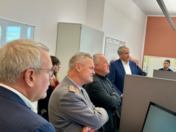 Landrat Götz Ulrich, Generalarzt Dr. Bruno Most und Rüdiger Erben hören den Erläuterungen von Matthias Hold zur neuen Integrierten Leitstelle des Burgenlandkreises zu.